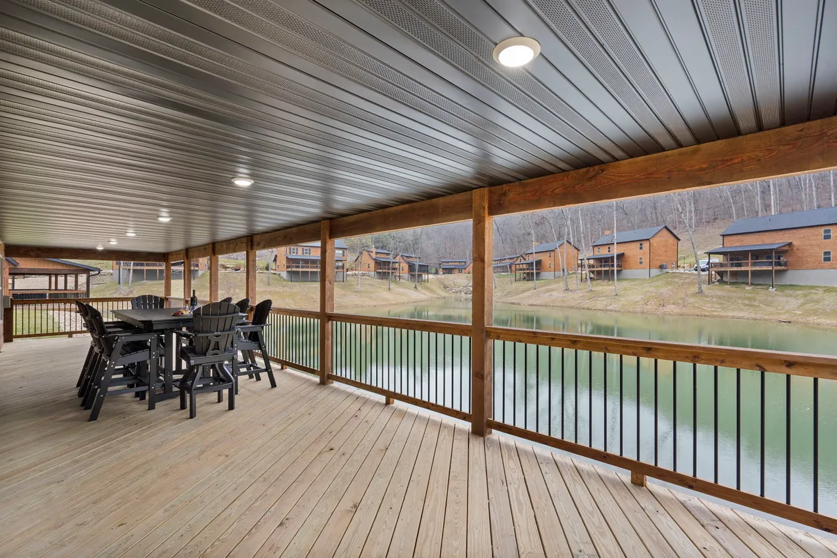 An outdoor dining area is set near the water, surrounded by lush greenery and cabins. The setting invites guests to enjoy meals outdoors, with the calm water and scenic landscape providing a peaceful backdrop.