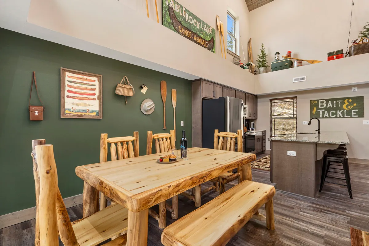 A cozy dining area with a large wooden table surrounded by handcrafted chairs, artwork on the walls, and an adjacent kitchen equipped with modern appliances. The mood is communal and inviting, showcasing family meals, celebrations, and shared cooking experiences.